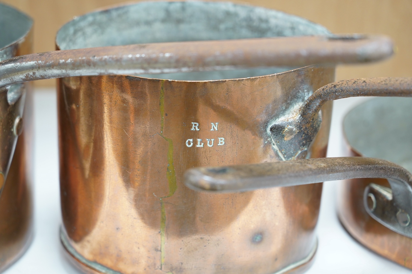 Three copper pans, one stamped RN Club, largest 63cm. Condition - fair